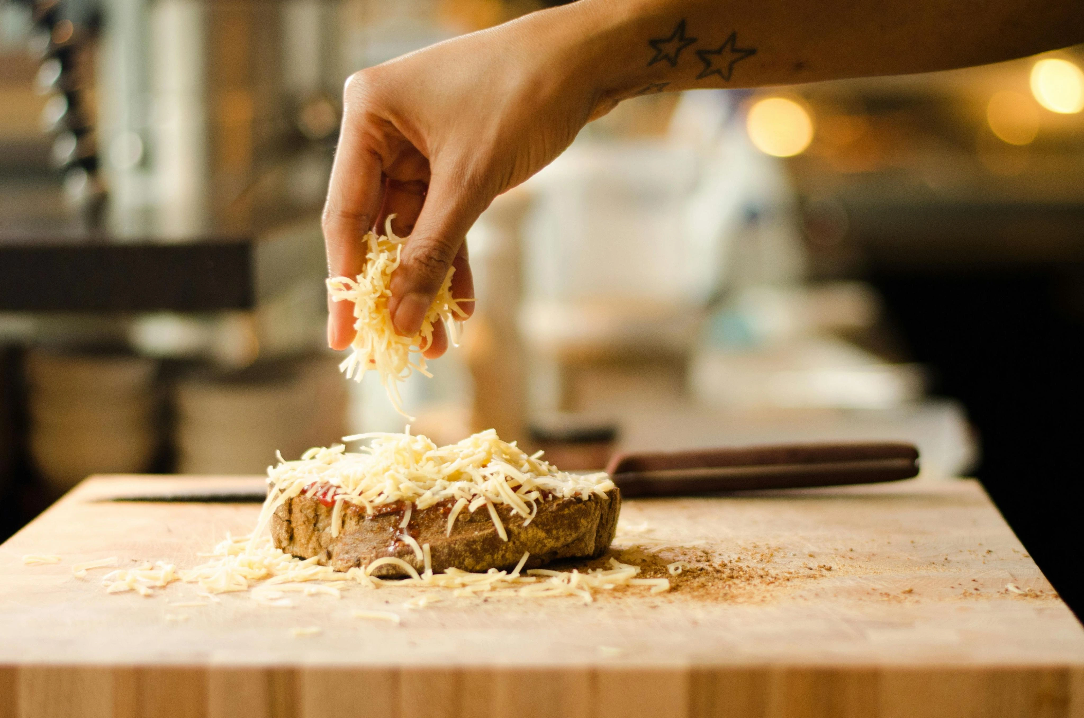 Shredded cheese being sprinkled over toast